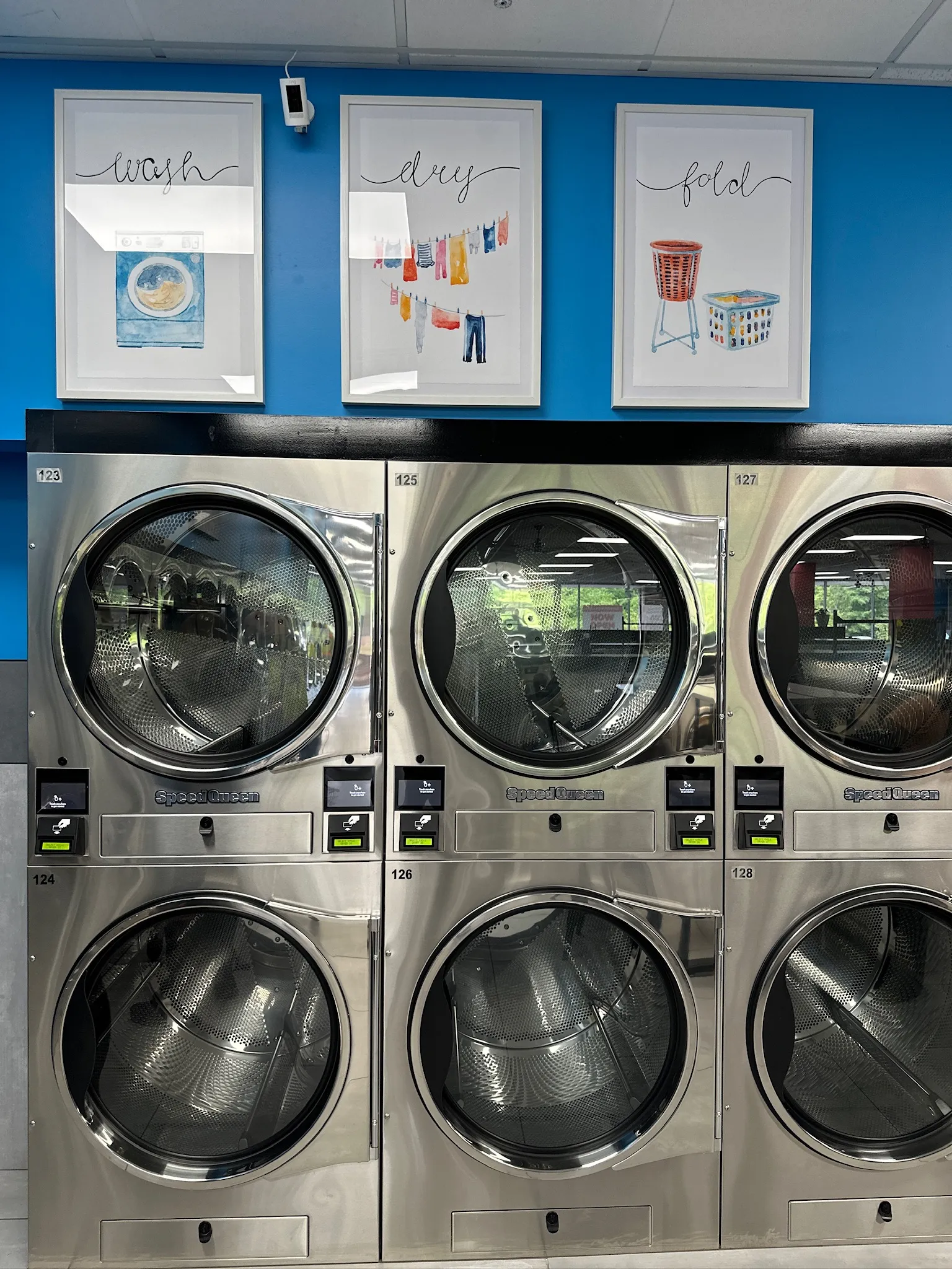 Row of commercial dryers offering free drying service at Lux Laundromat